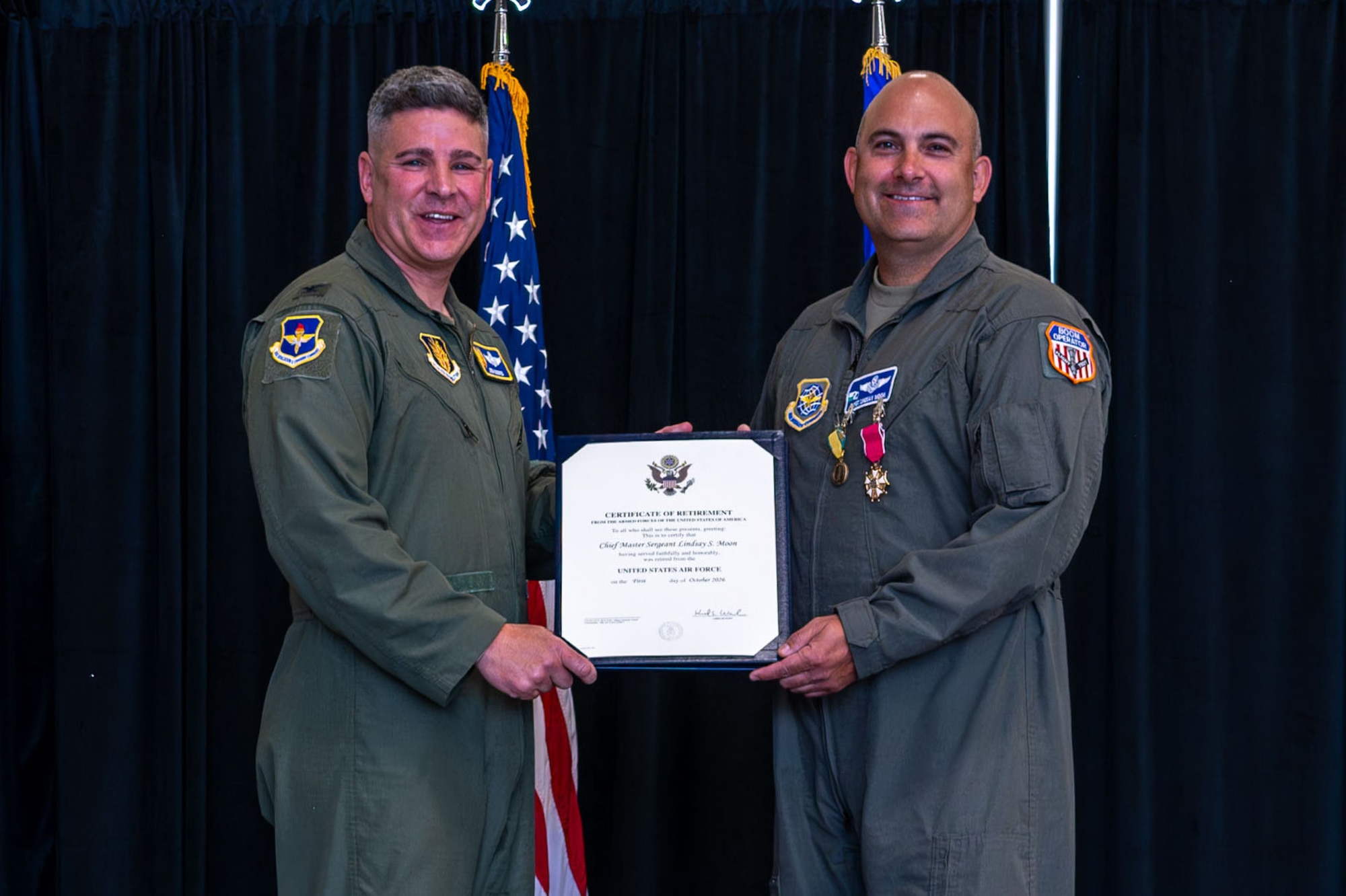 U.S. Air Force Col. Joshua Moores, left, 97th Air Mobility Wing deputy commander, presents certificate of retirement to Chief Master Sgt. Lindsay Moon, right, former 92nd Air Refueling Wing command chief, at Fairchild Air Force Base, Washington, June 16, 2026.