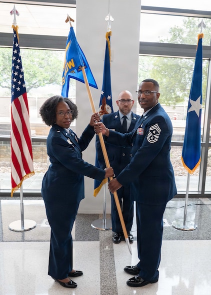 Chief Master Sgt. Marcus D. Washington, outgoing command chief of the 59th Medical Wing, passes the guidon to Brig. Gen. Gwendolyn A. Foster, commander of the 59th Medical Wing, during a Change of Responsibility Ceremony at the Wilford Hall Ambulatory Surgical Center, Joint Base San Antonio-Lackland, Texas, June 12, 2026.