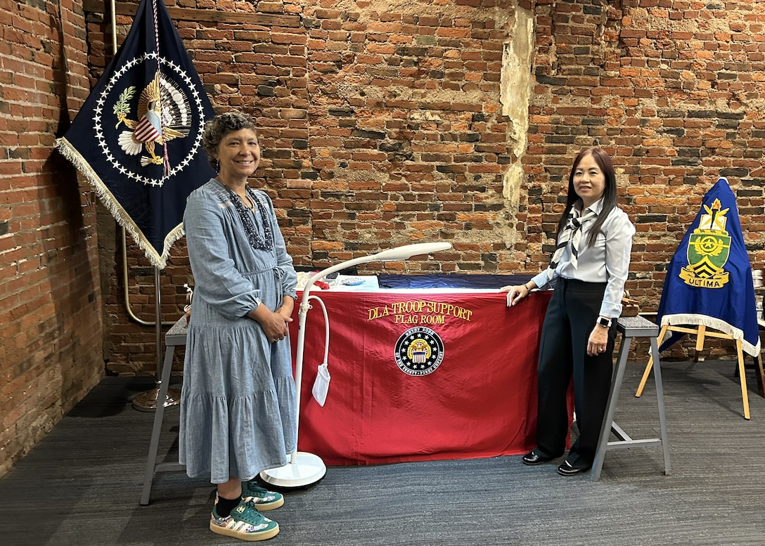 two women stand in front of a flag display