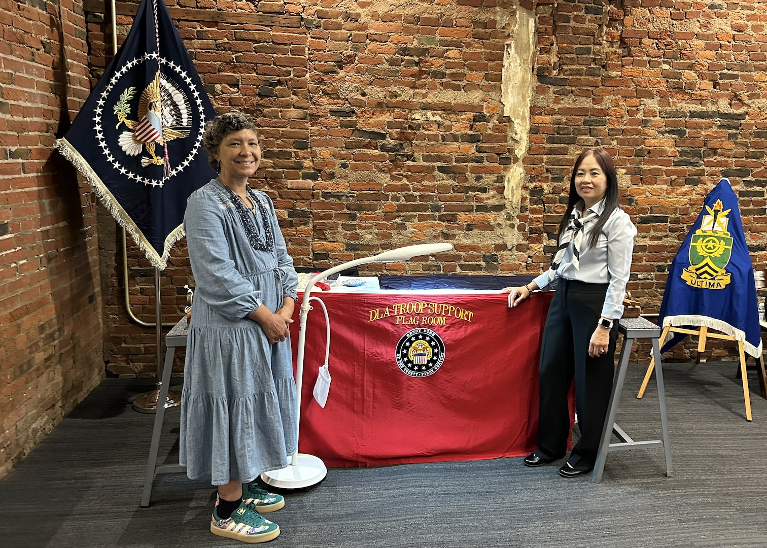 two women stand in front of a flag display