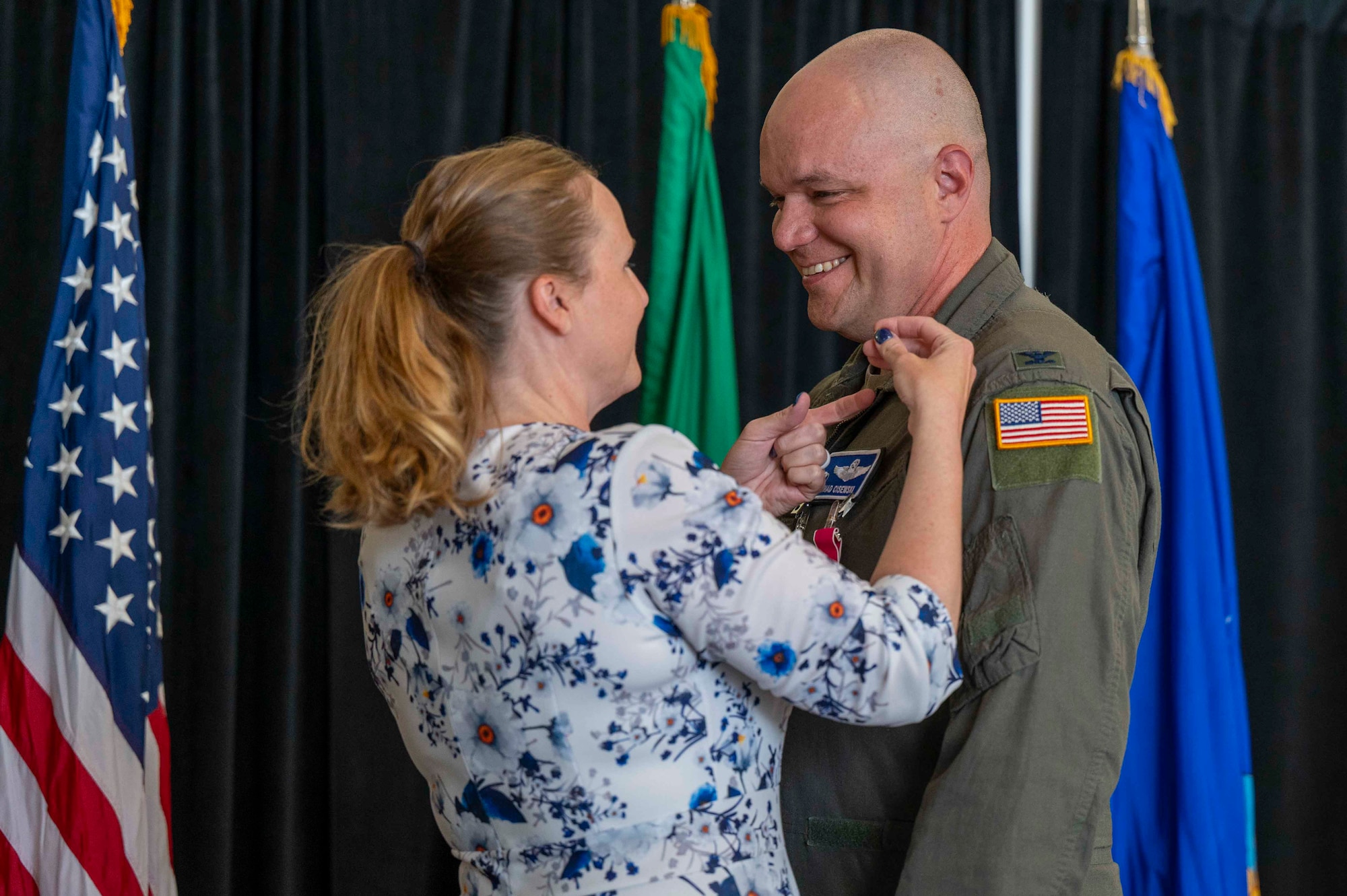 Former wing commander's spouse places a pin on her husband's uniform.