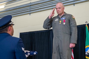 Former wing commander salutes U.S. flag.