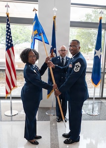 Chief Master Sgt. Marcus D. Washington, outgoing command chief of the 59th Medical Wing, passes the guidon to Brig. Gen. Gwendolyn A. Foster, commander of the 59th Medical Wing, during a Change of Responsibility Ceremony at the Wilford Hall Ambulatory Surgical Center, Joint Base San Antonio-Lackland, Texas, June 12, 2026.