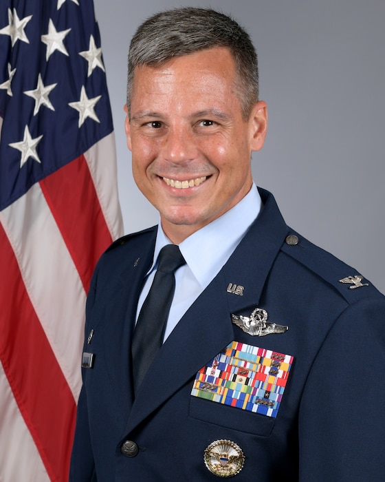 Biography photo in front of a flag.