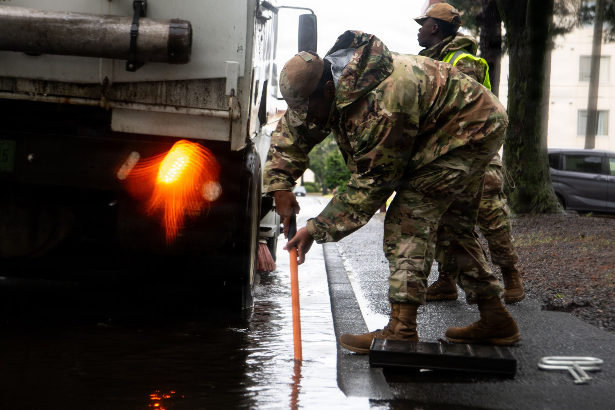 An Airman uses a shovel to break up settled debris inside a storm drain.