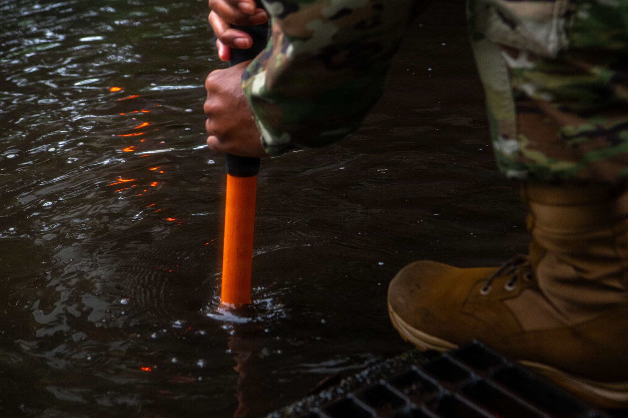 An Airman uses a shovel to break up settled debris inside a storm drain.