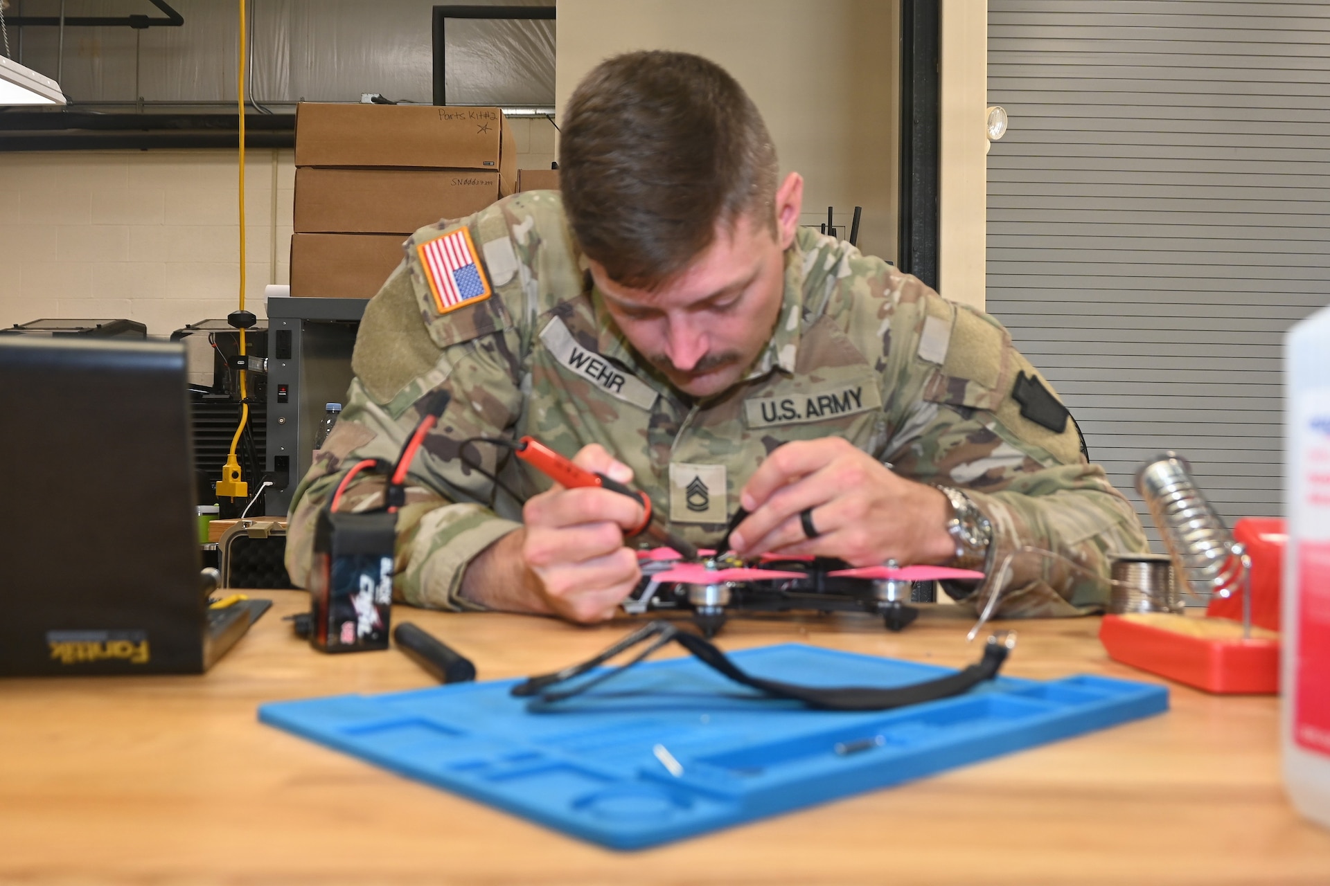 Sgt. 1st Class Brent Wehr, course manager for the 15X MOS transition course at the Unmanned Aircraft System Training and Innovation Facility at Fort Indiantown Gap, solders a part on a UAS on June 10, 2026. (Pennsylvania National Guard photo by Brad Rhen)