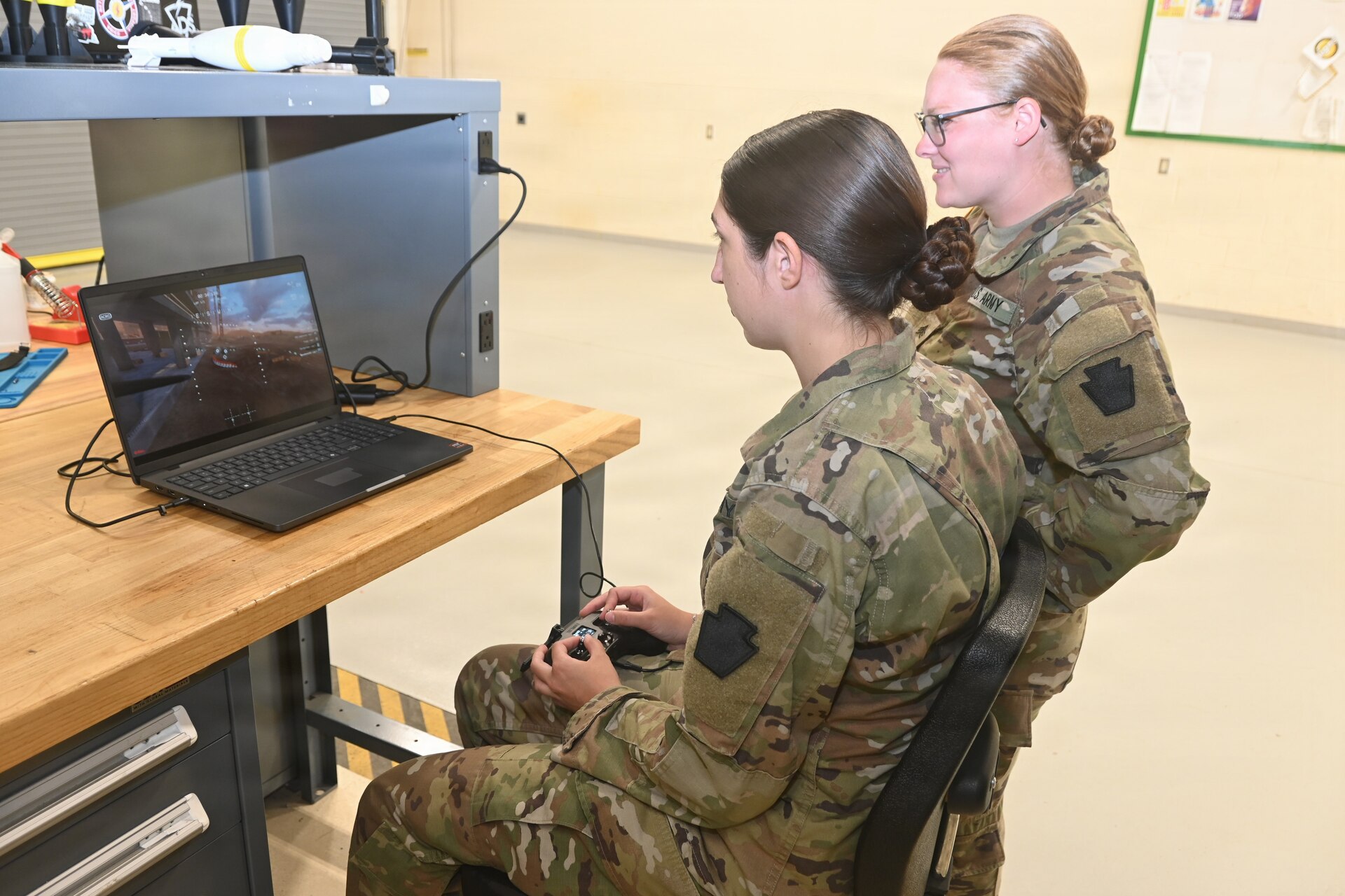 Sgt. Sophia Staskowski, left, uses a drone simulator, while Sgt. Syerra Freeman watches June 10, 2026, at the Unmanned Aircraft System Training and Innovation Facility at Fort Indiantown Gap, Pennsylvania. Both Soldiers are members of Mike Company, 56th Mobile Brigade Combat Team and work full-time at the UAS TIF. (Pennsylvania National Guard photo by Brad Rhen)