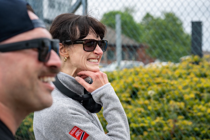 A close-up of a man and a woman in athletic attire and sunglasses smiling, while standing outside.
