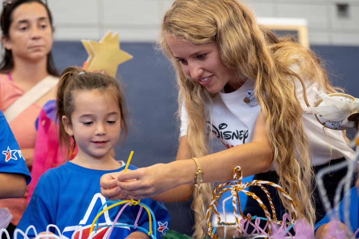 A Disney Volunteer helps a military child craft an item during a Blue Star Families event at MacDill Air Force Base, Florida, June 16, 2026. The Second Lady of the United States,Usha Vance, attended the event to read a children’s book to children of military members. During the event, approximately 125 children received Disney books and met Mickey Mouse along with other surprises. (U.S. Air Force photo by Airman 1st Class Nelvis Sera)