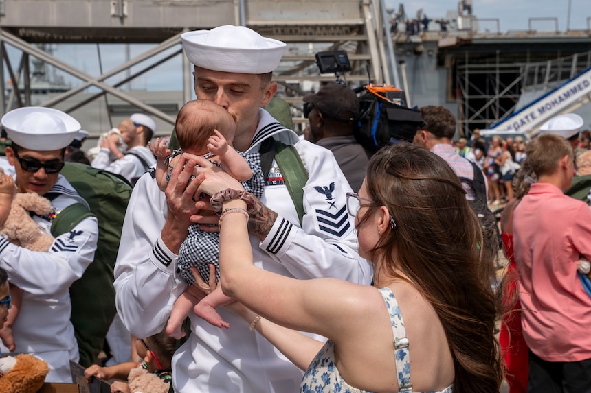 Cryptologic Technician Maintenance 1st Class Dorian Marko, assigned to Arleigh Burke-class guided-missile destroyer USS Mitscher (DDG 57), embraces his child on the pier at Naval Station Norfolk following a historic 11-month deployment to the U.S. 5th and 6th Fleet areas of operation.
