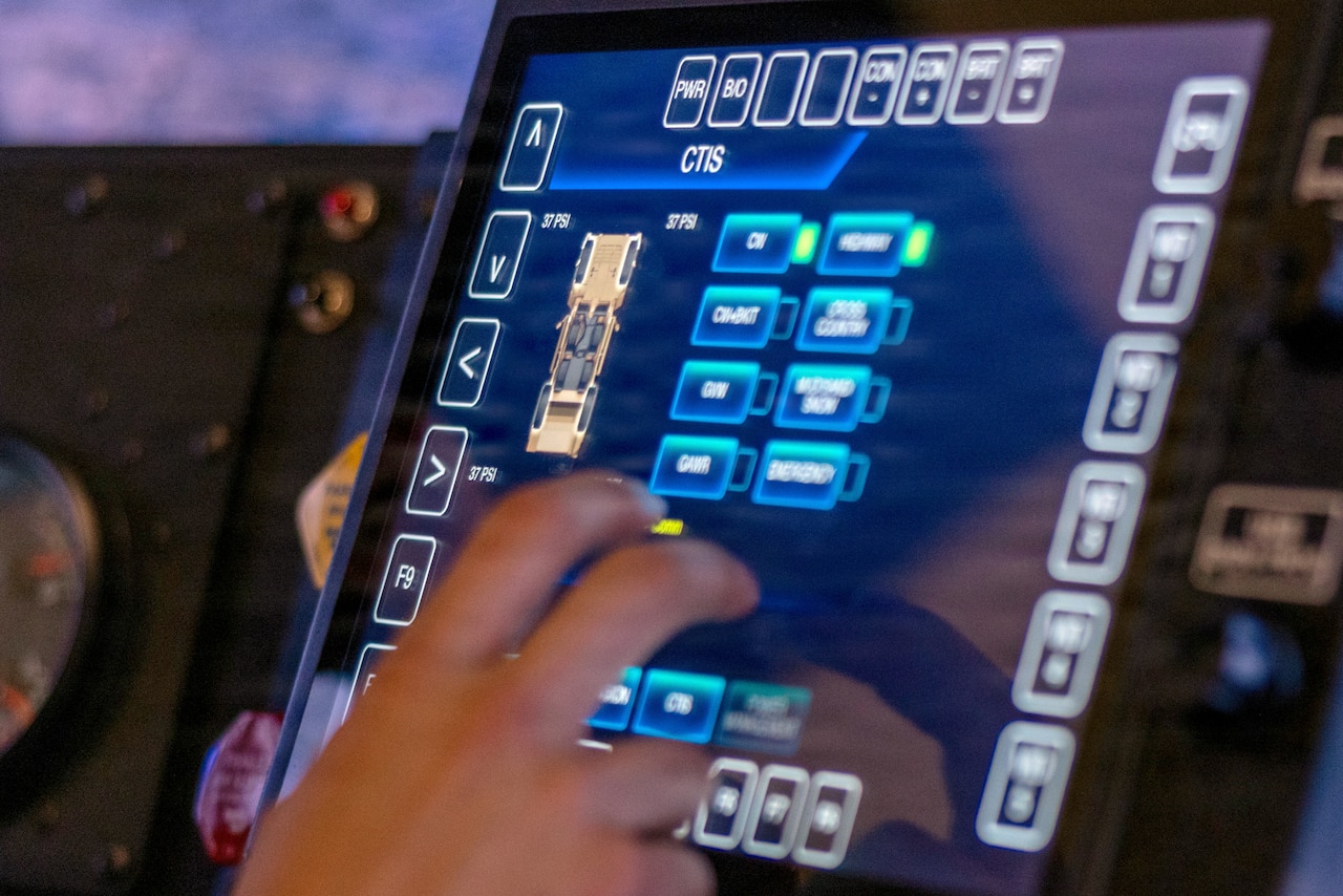 A close-up of a hand tapping the screen in a driving simulator.
