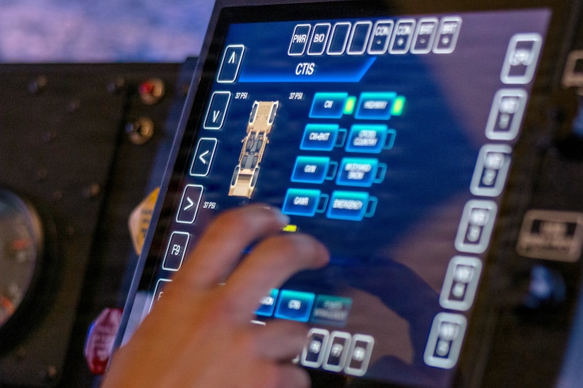 A close-up of a hand tapping the screen in a driving simulator.