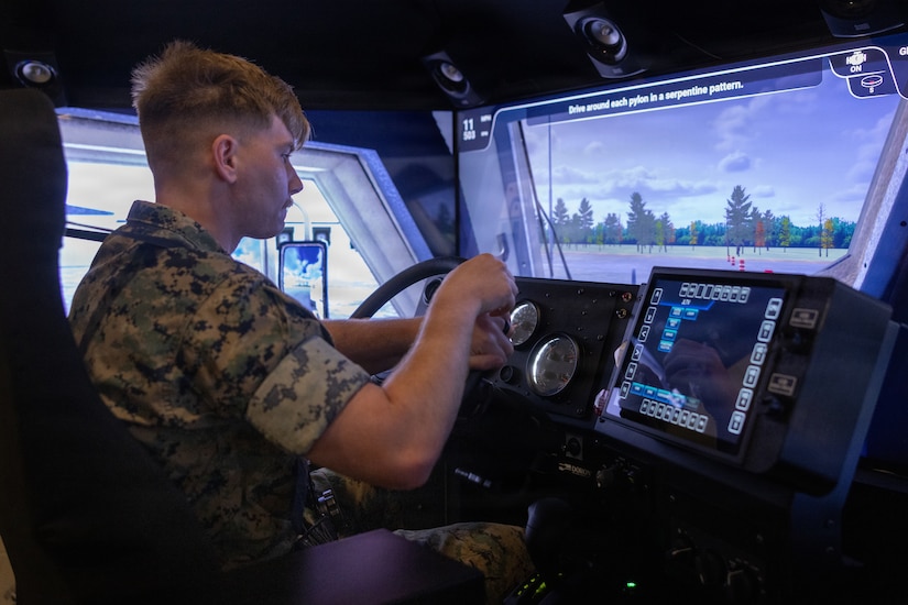 A man wearing a military camouflage uniform operates a driving simulator.