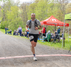 Kosteczko crosses the finish line of an ultra marathon.