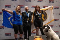 Retired U.S. Air Force Maj. Lillian Warner, left, U.S. Army Capt. Channda Mitchell, center, and U.S. Army Sgt. Ann Knox, right celebrate winning silver, gold, and bronze respectively during the powerlifting competition at the 2026 Warrior Games.