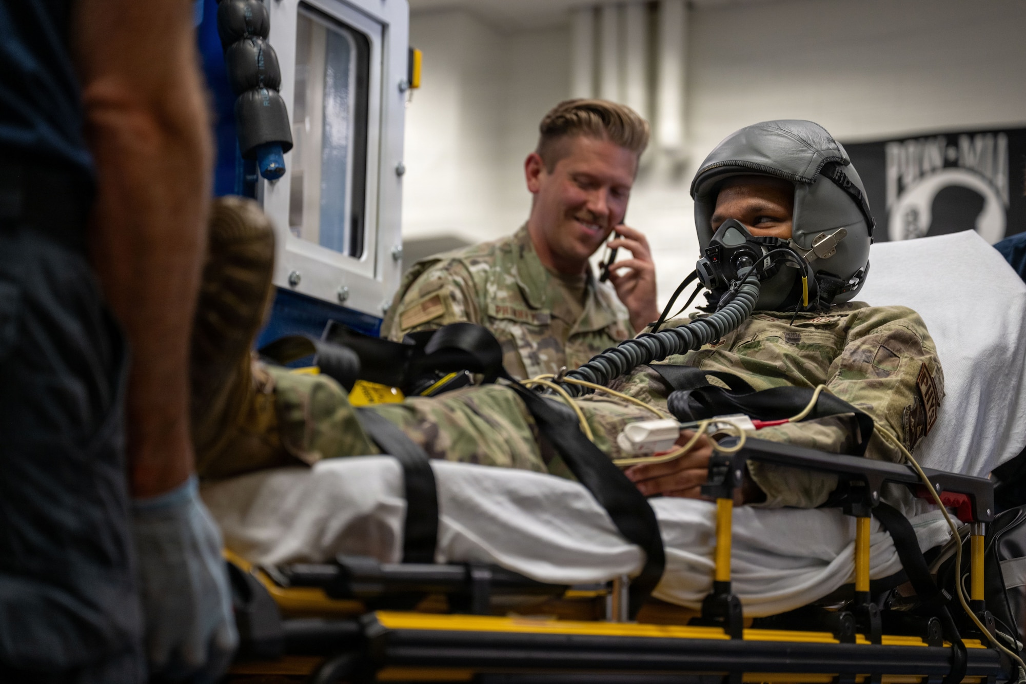 A man with a helmet and mask lays on a transportable ambulance bed.