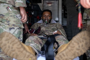 A male airman lies on a transportable bed inside an ambulance.