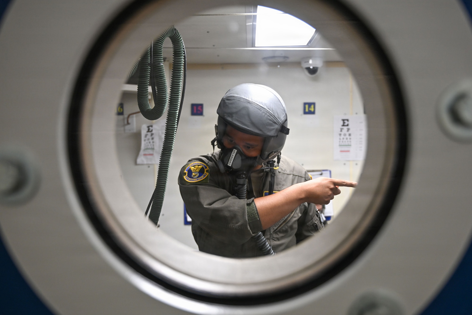 A man is seen through a window. He has a helmet and mask on and he's pointing.
