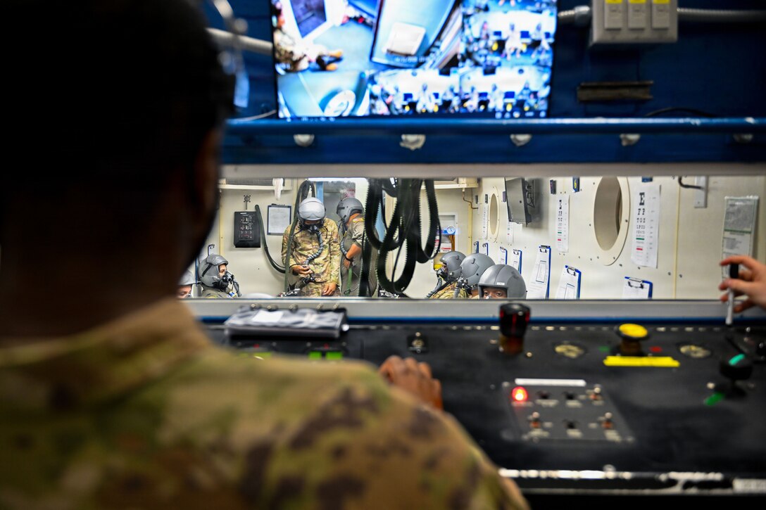 Airmen are observed inside of a chamber.