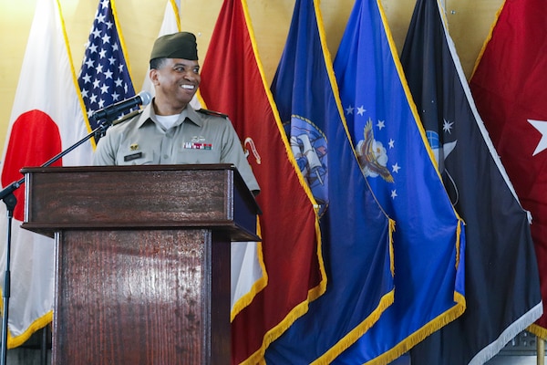 A man wearing a military uniform stands on stage behind a podium speaking.
