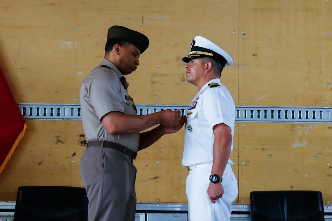 People wearing military uniforms stand on stage