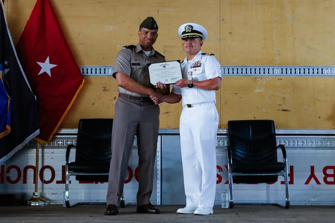 People wearing military uniforms stand on stage