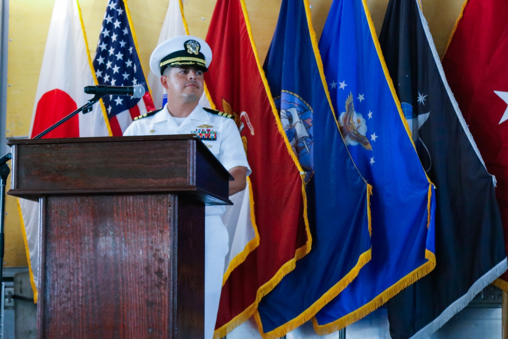 A man a wearing military uniform stand on stage behind a podium speaking