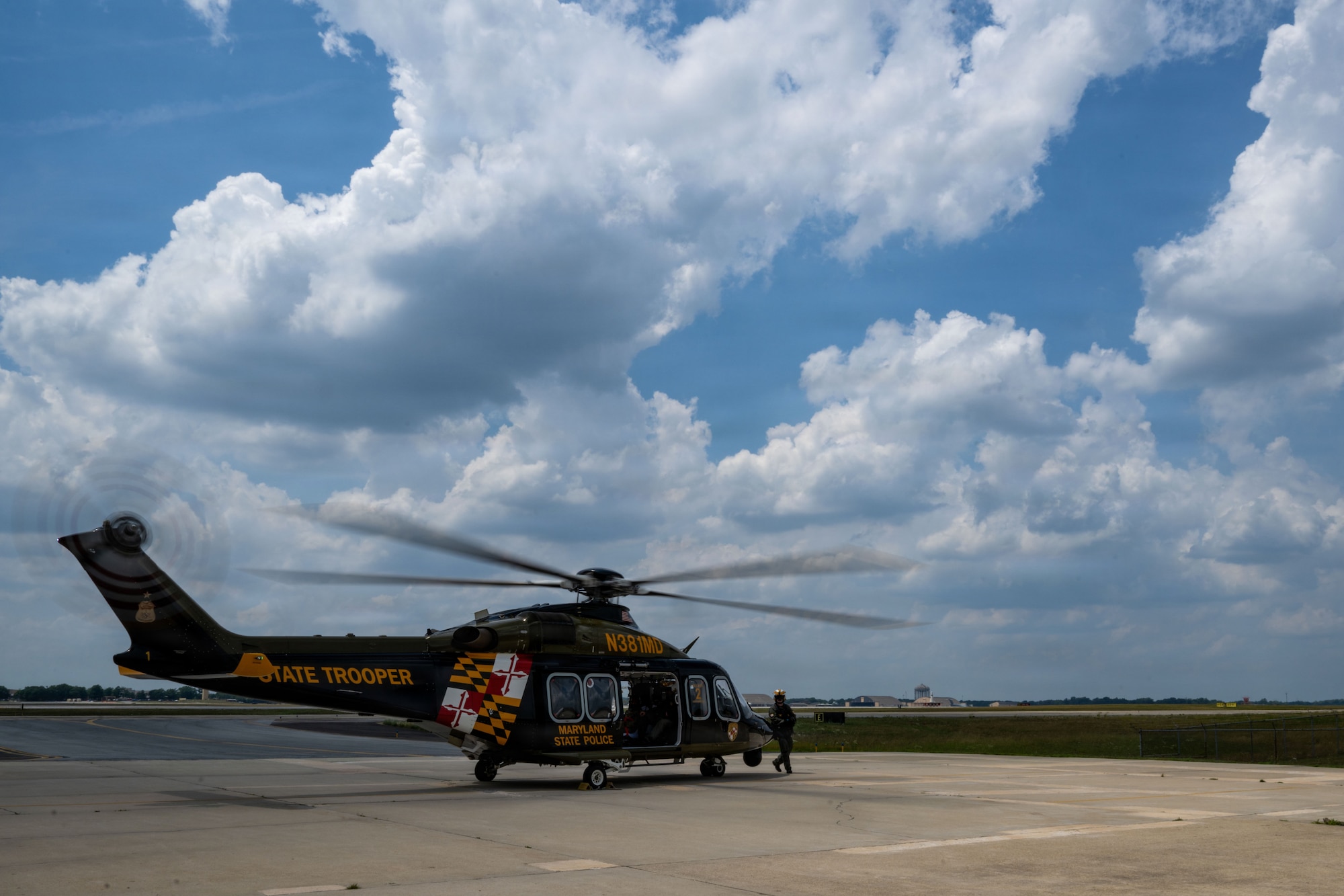 A helicopter sits on a flight pad on a sunny but cloudy day.