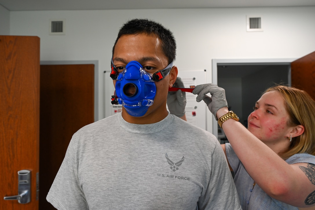 Civilian puts a mask on an Airman. (U.S. Air Force photo by Crista Mary Mack)