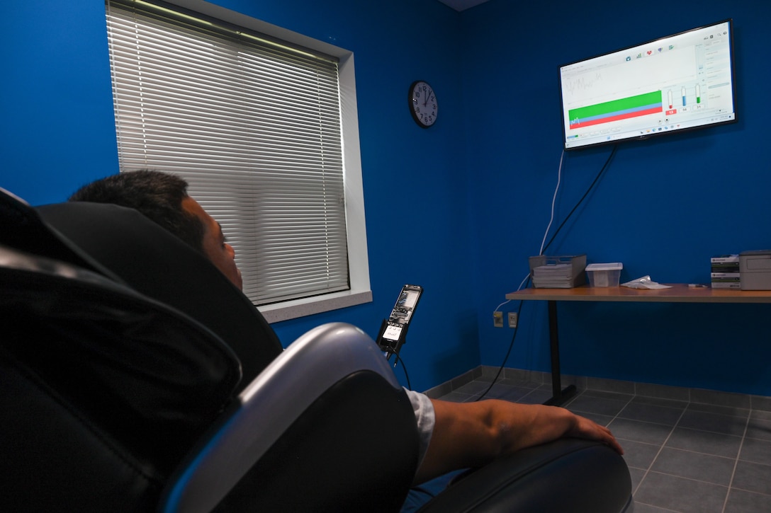 Airman sits in a massage chair looking at monitor on the wall.(U.S. Air Force photo by Crista Mary Mack)