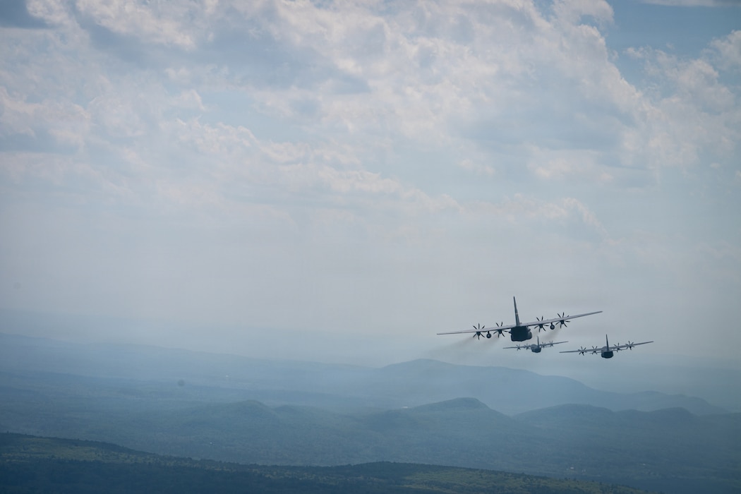 U.S. Air National Guard air crews from the 103d Airlift Wing and 143d Airlift Wing conduct joint tactical interfly operations over sections of Massachusetts and Vermont at dusk with blue mountains.