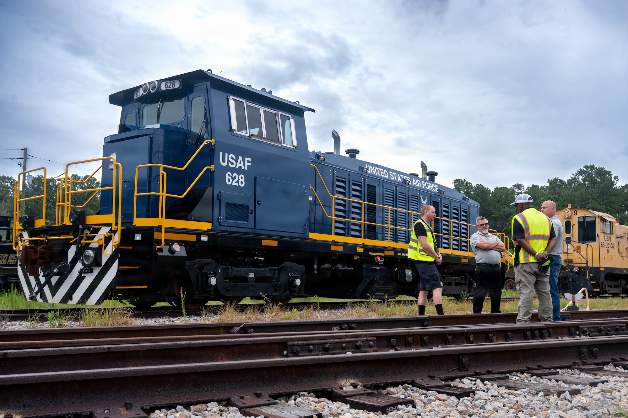 A photo of four men conversing in front of a locomotive.
