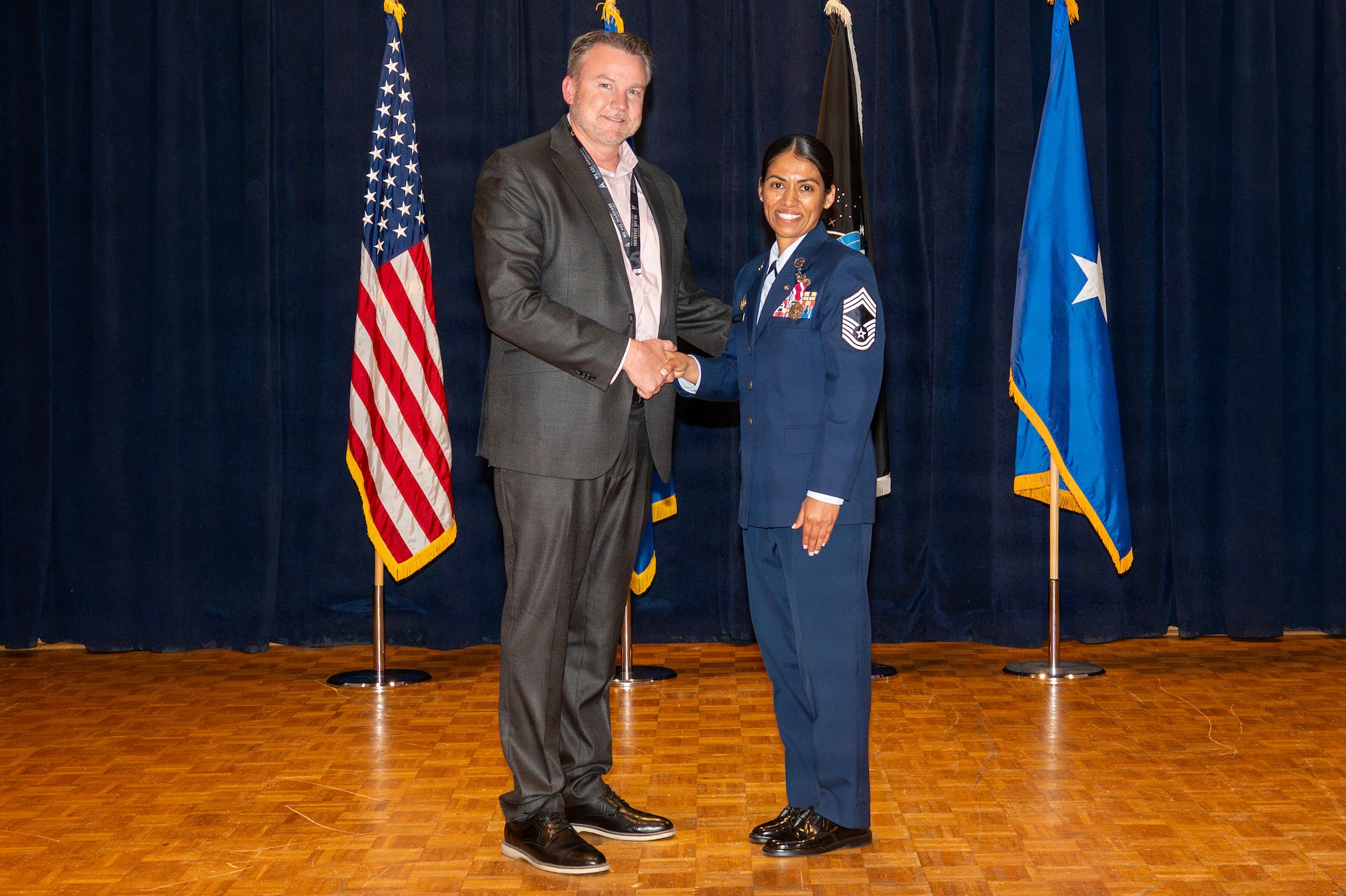 Two people stand together and shake hands
