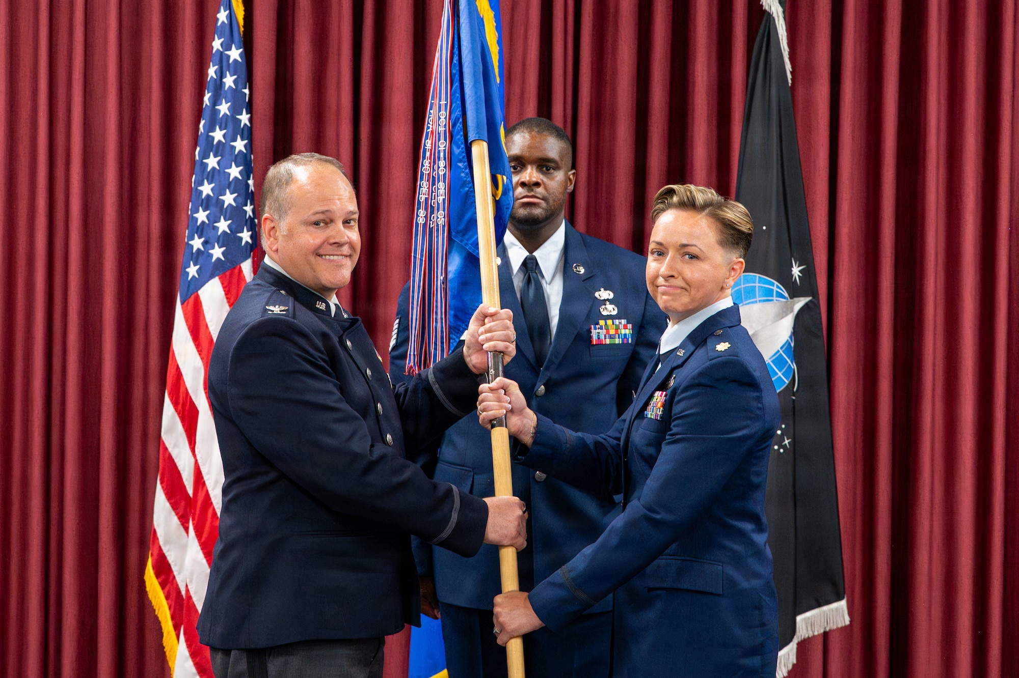 Two people exchange a flag