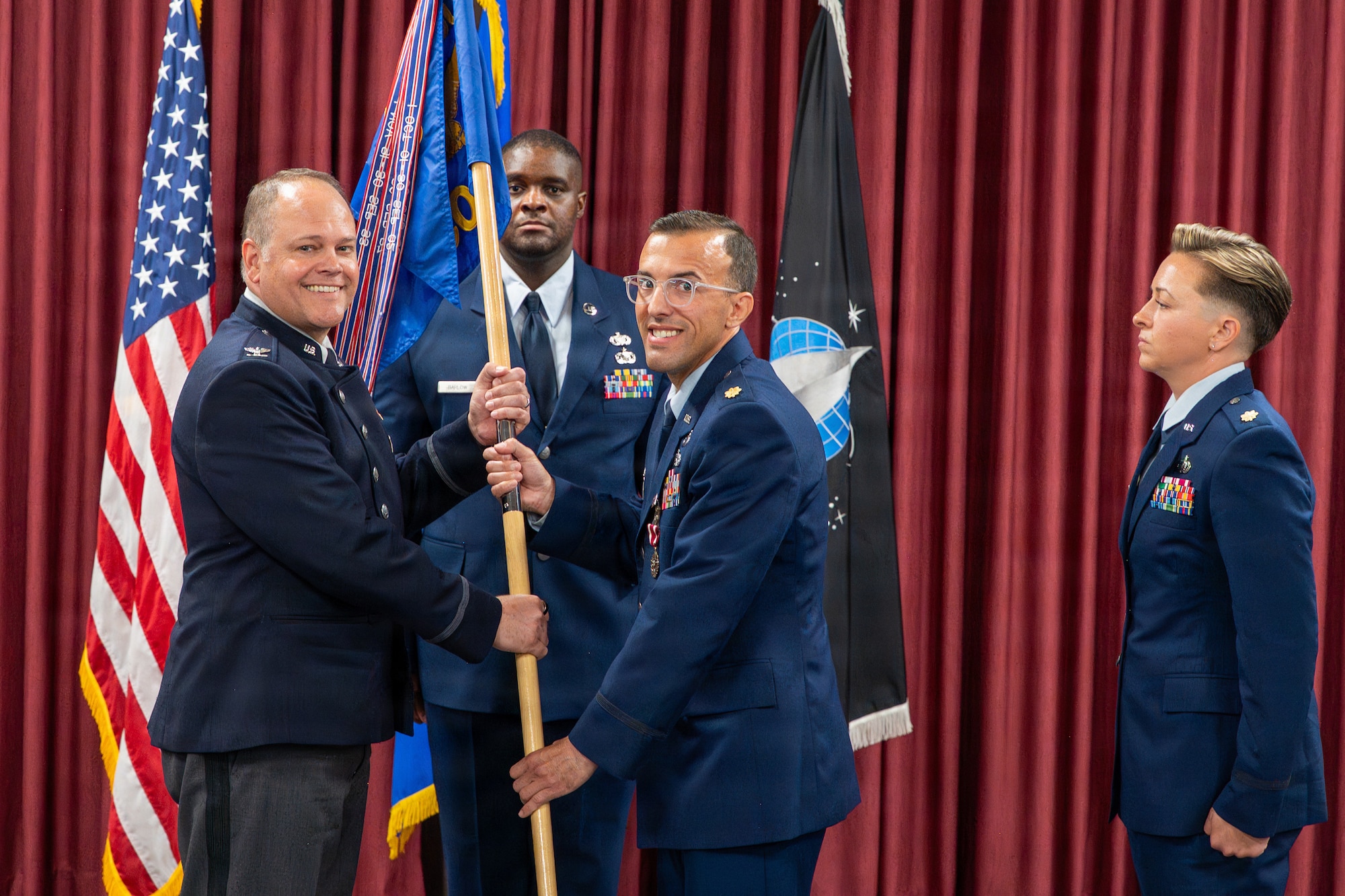 Two people exchange a flag as one watches