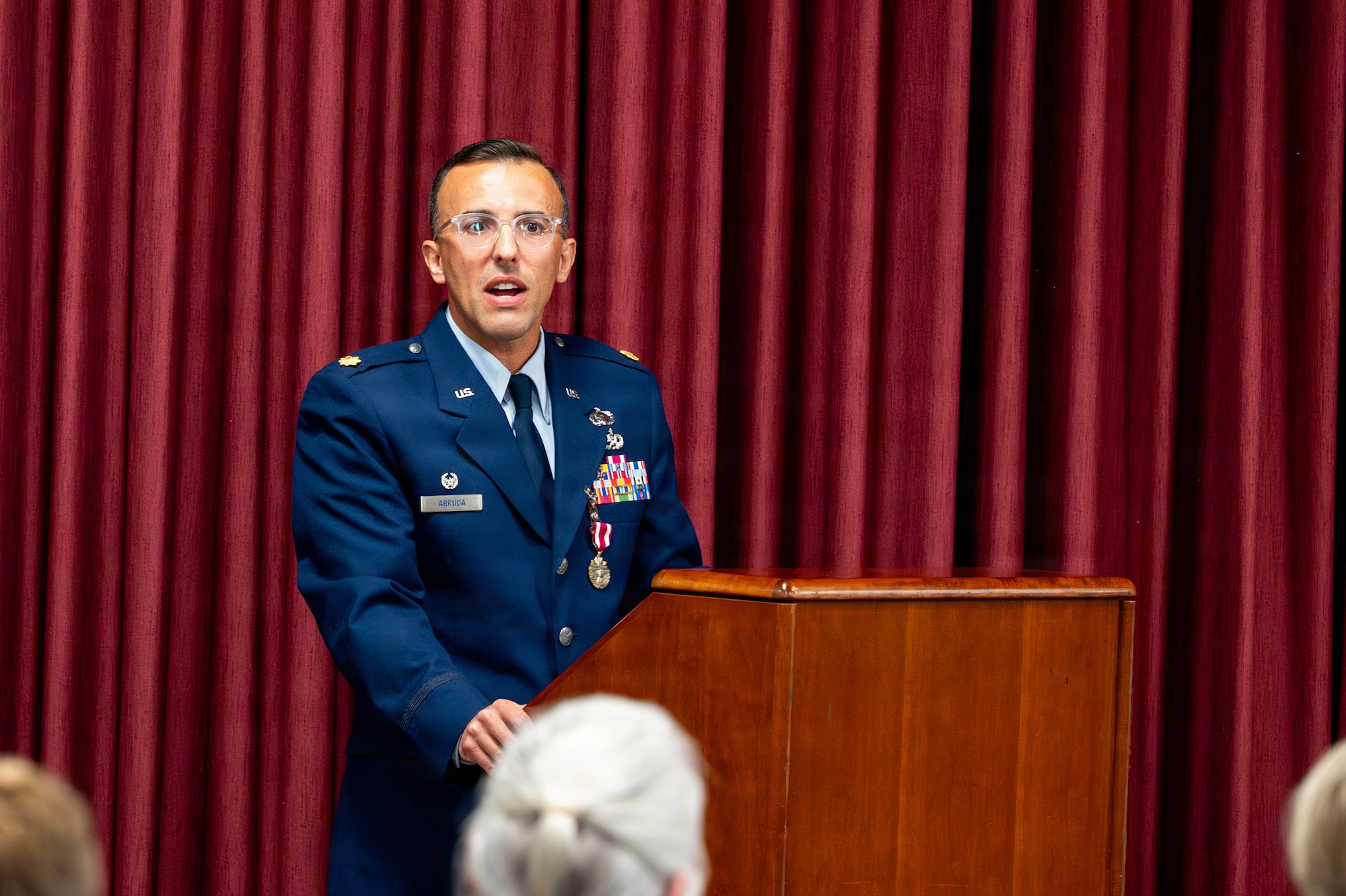 A person stands and speaks behind a podium
