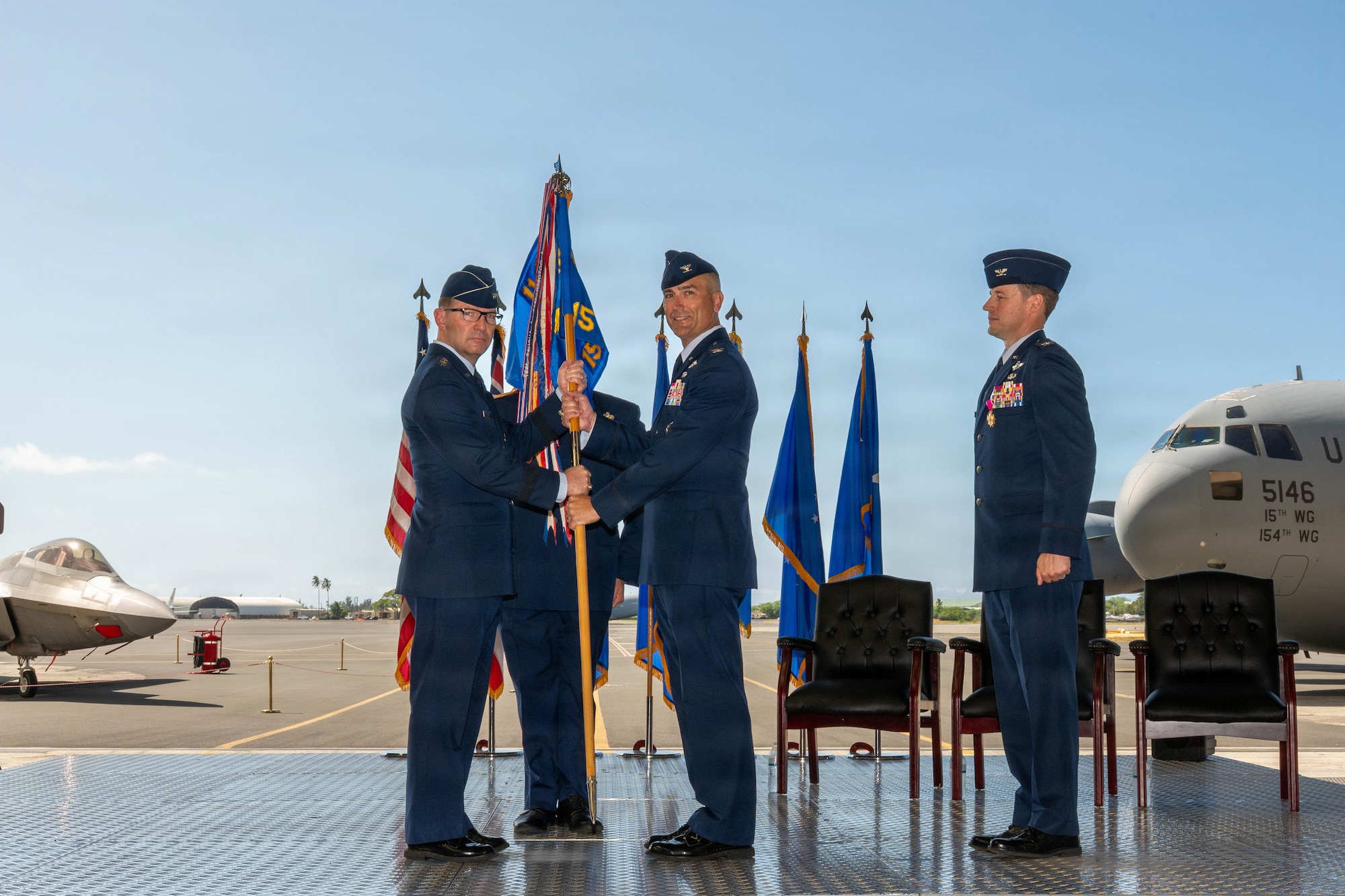 U.S. Air Force Lt. Gen. Robert Davis, Alaskan North American Aerospace Defense Command Region, Alaskan Command and Eleventh Air Force commander, passes the 15th Wing guidon to Col. Kyle Clinton, incoming 15th Wing commander, during the wing change of command ceremony at Joint Base Pearl Harbor-Hickam, Hawaii, June 18, 2026. Clinton served as the 437th Operations Group commander prior to taking command of the 15 WG. (U.S. Air Force photo by Senior Airman Lauren Torres)