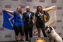 Retired U.S. Air Force Maj. Lillian Warner, left, U.S. Army Capt. Channda Mitchell, center, and U.S. Army Sgt. Ann Knox, right celebrate winning silver, gold, and bronze respectively during the powerlifting competition at the 2026 Warrior Games.