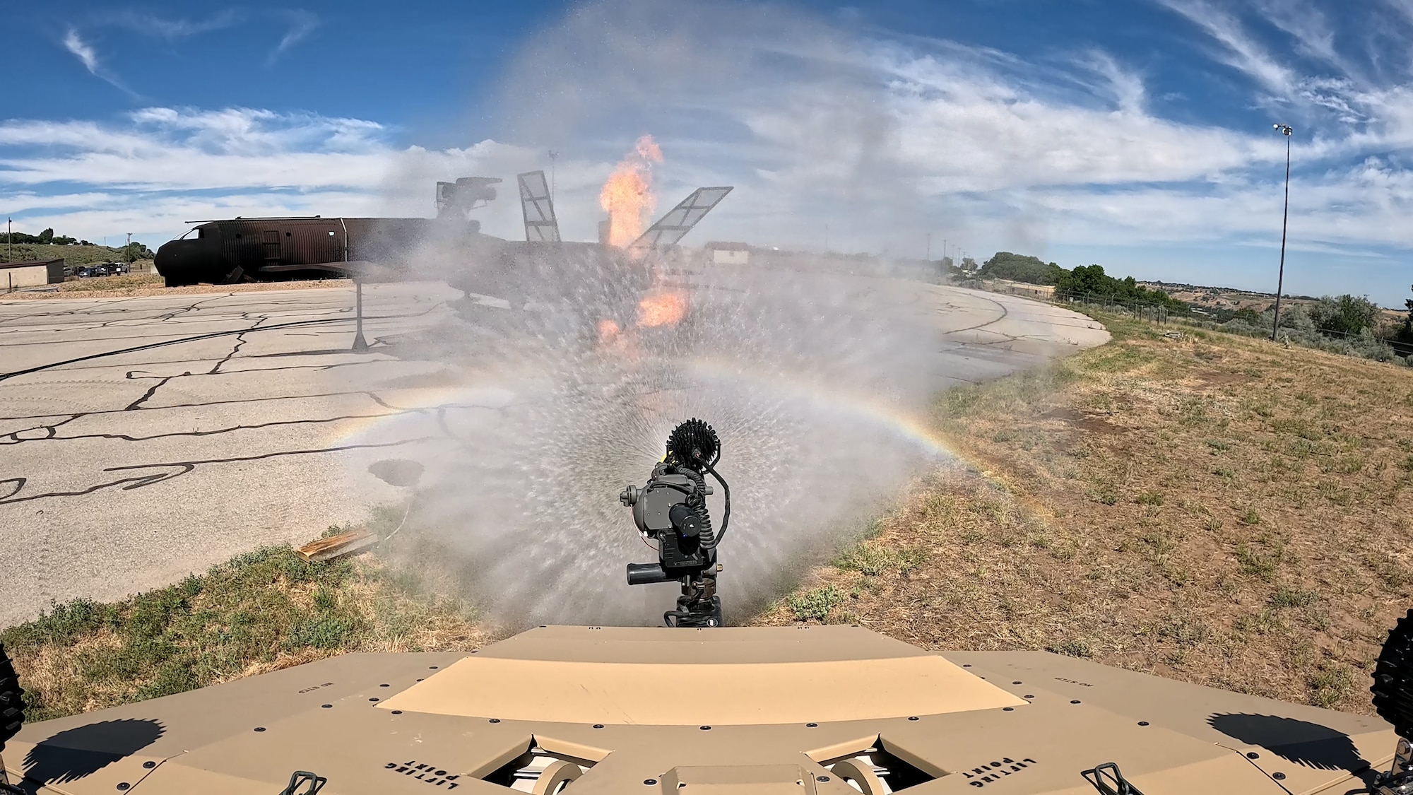 An interior view from the cab of the MARK 1 firefighting apparatus spraying water at a fiery F-35 prop.
