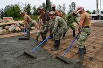U.S. Navy Sailors, assigned to Amphibious Construction Battalion (ACB) 1, rake cement over frames for a boat ramp during Baltic Operations (BALTOPS) 2026 in Liepaja, Latvia, June 17, 2026.
