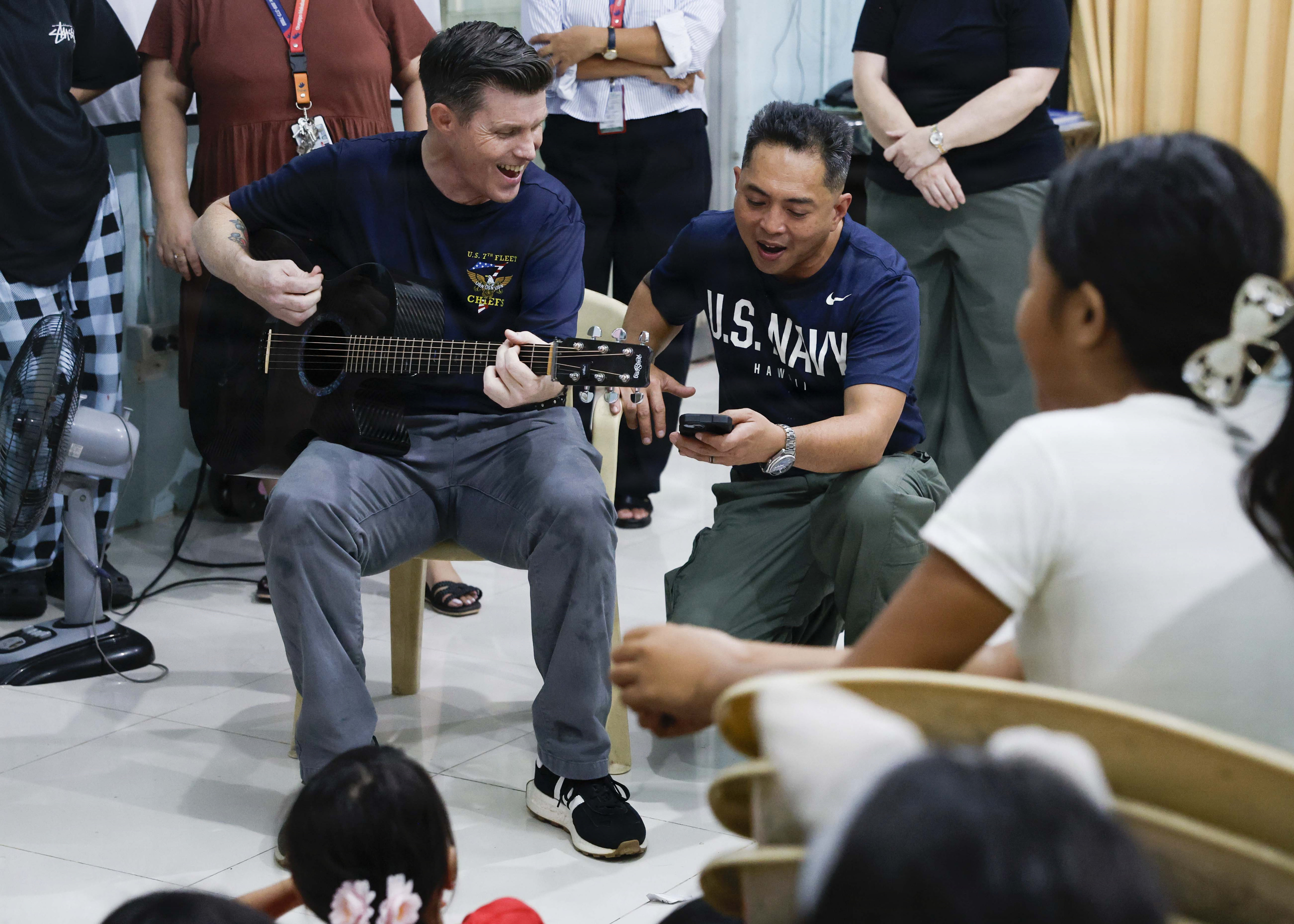 OLONGAPO CITY, Philippines (June 12, 2026) – U.S. Navy Capt. Robert Reyes, right, mission commander of Pacific Partnership 2026 (PP26), and U.S. Navy Chief Musician James Choate, assigned to PP26, sing to children during a PP26 community outreach and engagement event at the Olongapo Social Development Center in Olongapo City, Philippines, June 12, 2026.