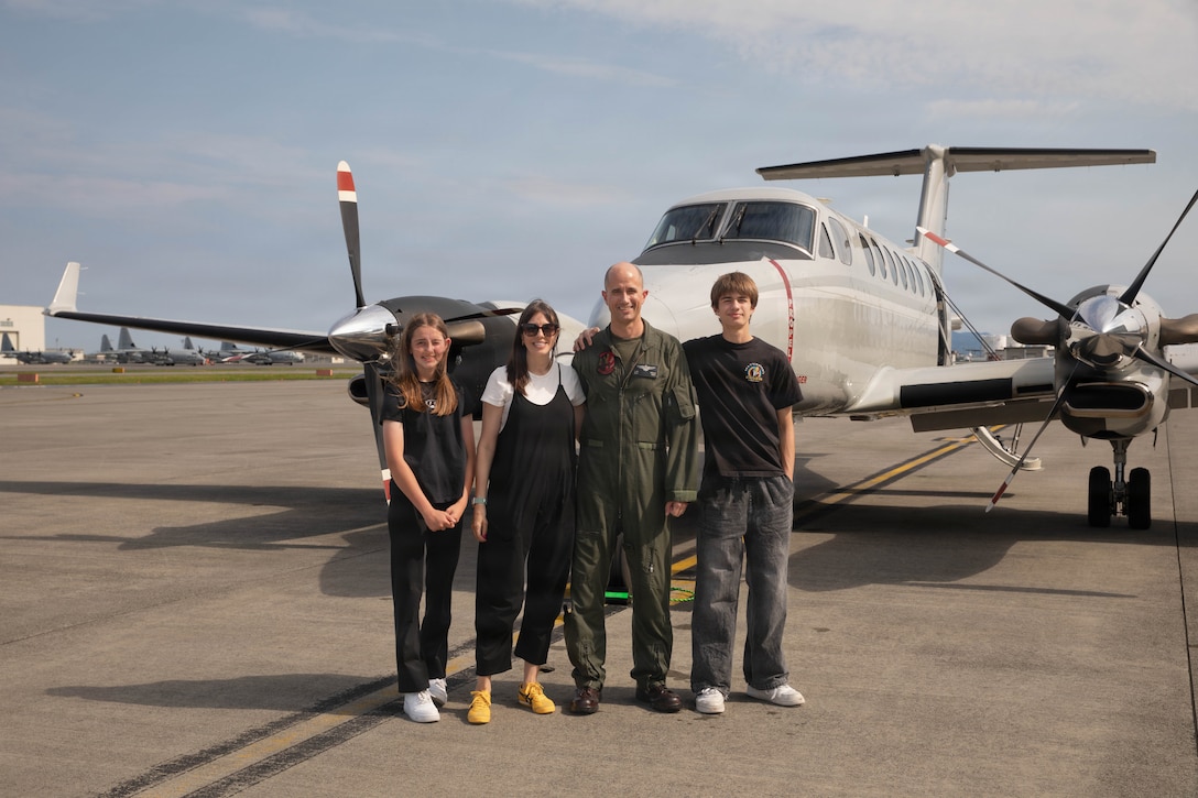 U.S. Marine Corps Maj. Jon Weeks, a UC-12W Huron pilot with Headquarters and Headquarters Squadron (H&HS), Marine Corps Air Station Iwakuni, and a native of Broken Arrow, Oklahoma, poses for a photo with his family after his final flight at MCAS Iwakuni, Japan, June 12, 2026. A commander’s final flight is a long-standing aviation tradition marking the end of their tour of duty. (U.S. Marine Corps photo by Lance Cpl. Kenneth Garcia)