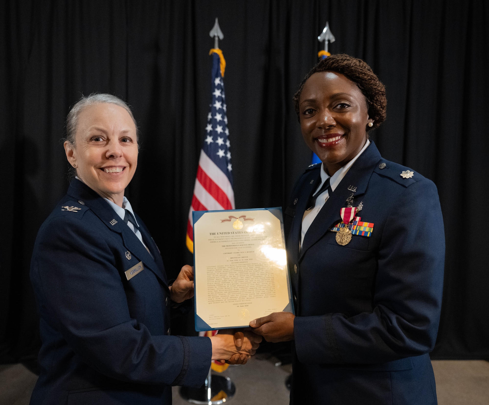 U.S. Air Force Col. Kelly Vermillion, Laughlin Medical Group commander, left, presents Lt. Col. Avis McCaslin, outgoing Laughlin Operational Medical Readiness Squadron (LOMRS) commander, with a certificate for the Meritorious Service Medal during the LOMRS change of command ceremony at Laughlin Air Force Base, Texas, June 18, 2026. The certificate recognized McCaslin's achievements during her tenure as LOMRS commander. (U.S. Air Force photo by Airman 1st Class Darryl Keith)