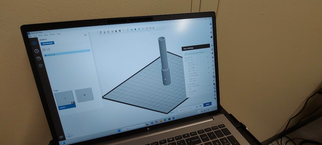 A computer monitor shows the 3D print in progress on its screen.