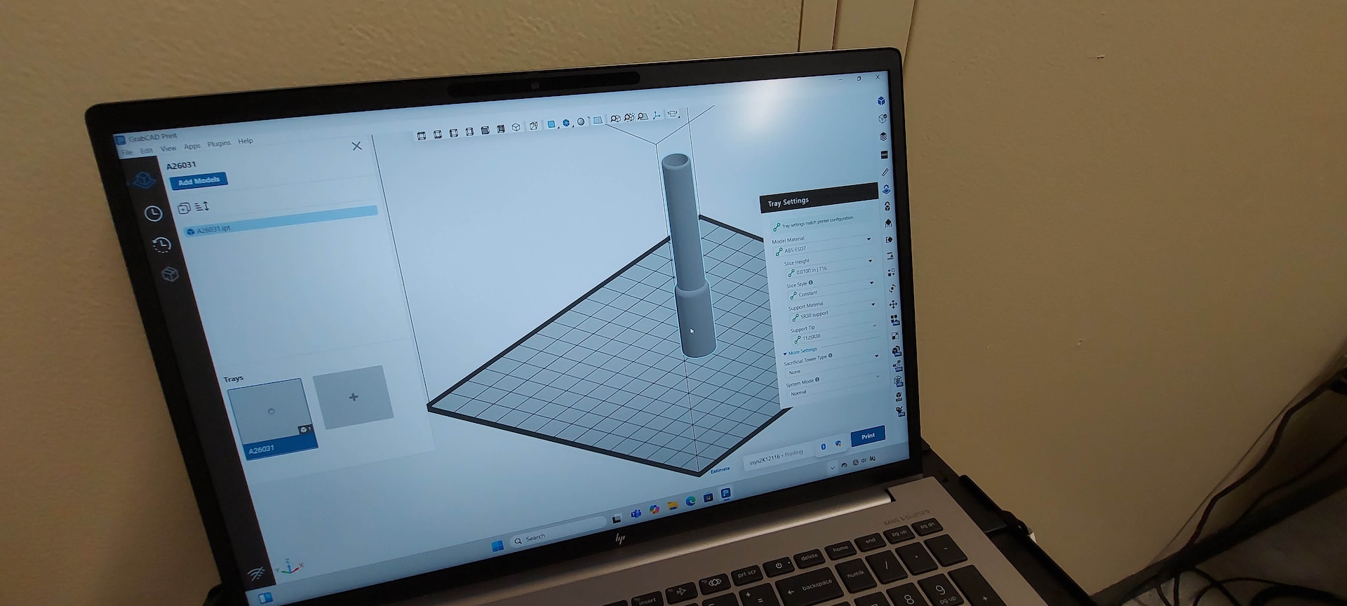 A computer monitor shows the 3D print in progress on its screen.