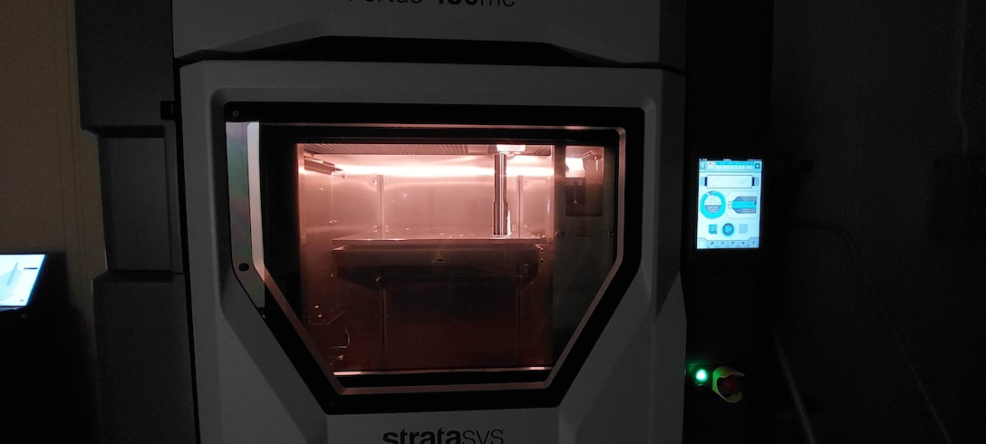 A object is being 3D printed in a chamber with a red light.
