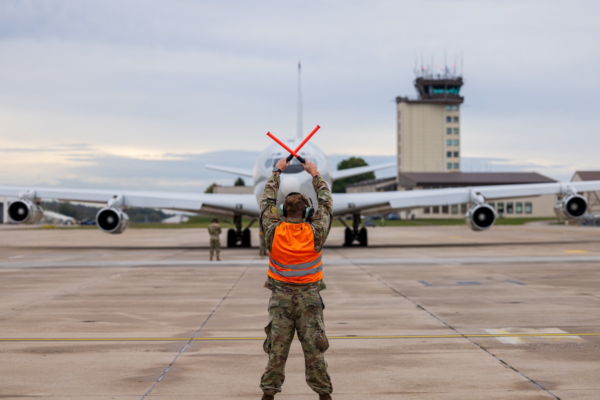 Military aircrew member guides an airplane on the airfield