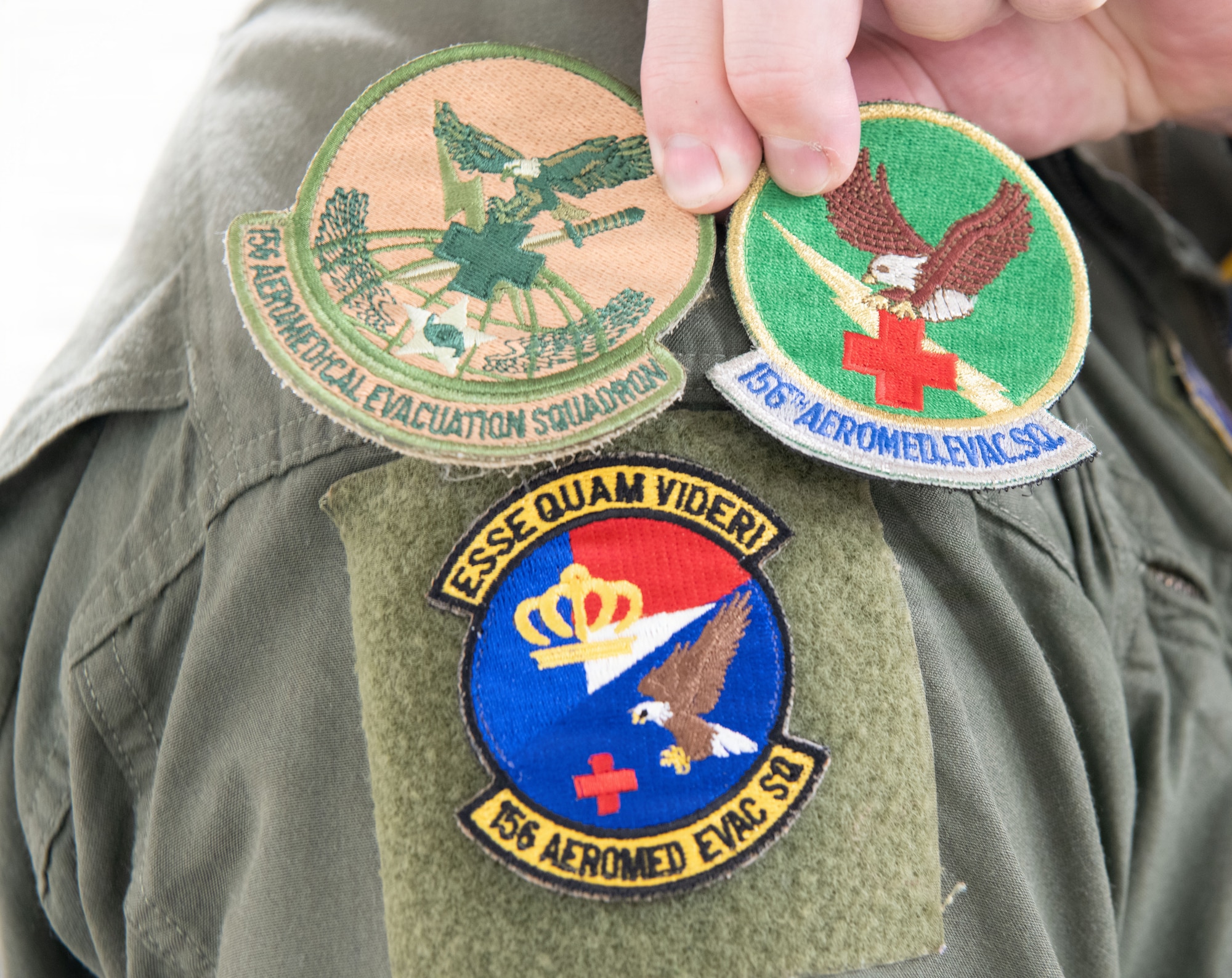 A member of the 156th Aeromedical Evacuation Squadron displays previous versions of the squadrons patch along with the new version during an emblem dedication ceremony on 6 June 2026 at the Charlotte Air National Guard base, North Carolina.