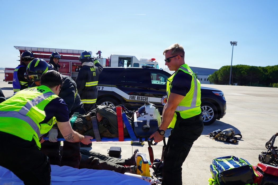 Hospital Corpsman 2nd Class John Paul Manikas and Hospital Corpsman 3rd Class Michael Blanchard, assigned to Naval Medical Readiness and Training Command (NMRTC) Rota, transport a simulated casualty during an Air Mishap exercise at Naval Station Rota, May 20, 2026. The training enhanced coordination among responding agencies and strengthened the readiness of Navy Medicine personnel to provide lifesaving care and medical support during operational, contingency, and emergency response missions. (U.S. Navy photo by Lt. Vanessa Bernales)